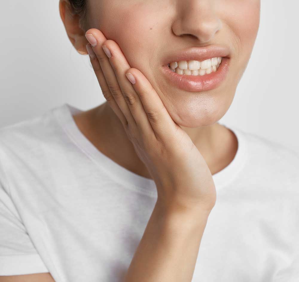 woman holding cheek sore tooth
